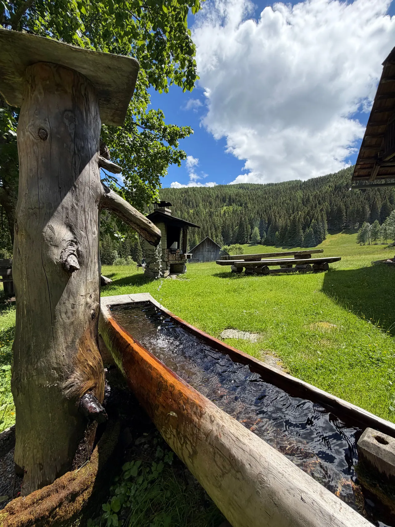 Der hölzerne Brunnen mit geschnitzter Figur und langem Trog