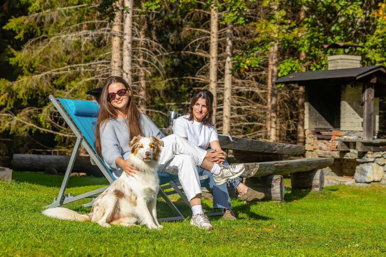 Zwei junge Frauen mit dem Hund auf der Wiese, eine im Liegestuhl