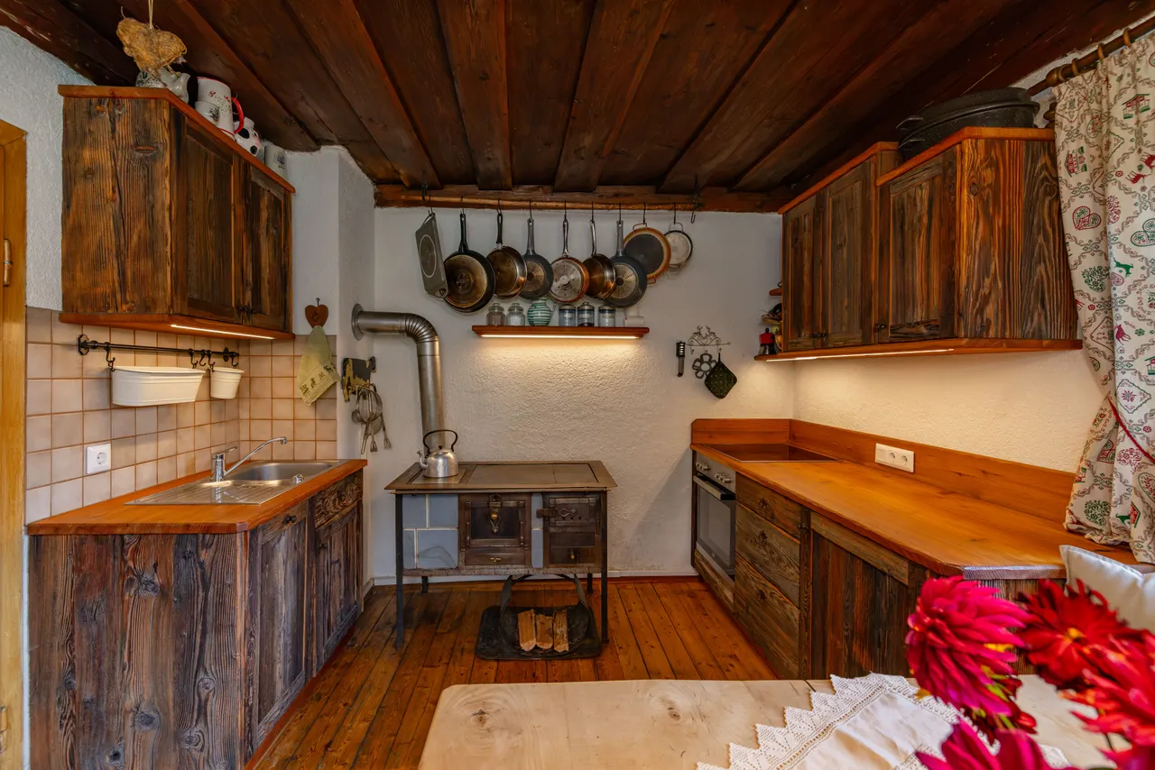 Küche mit Holzherd und hängenden Pfannen