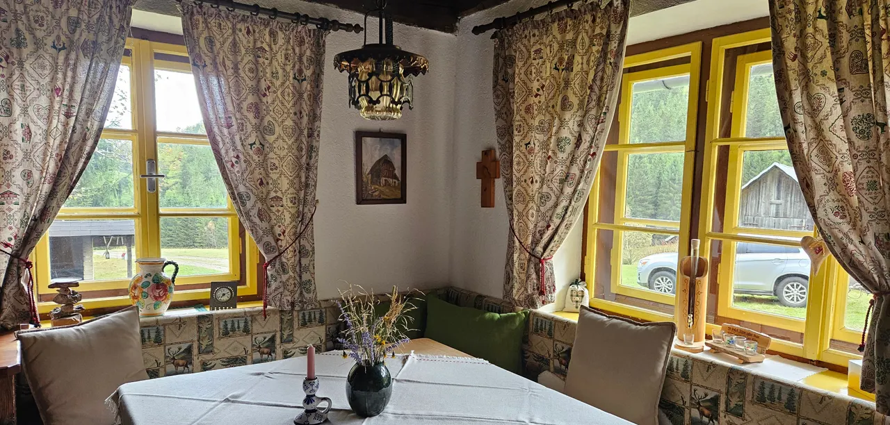 Der Essbereich der Hütte mit Blumenvorhängen und Panoramafenstern