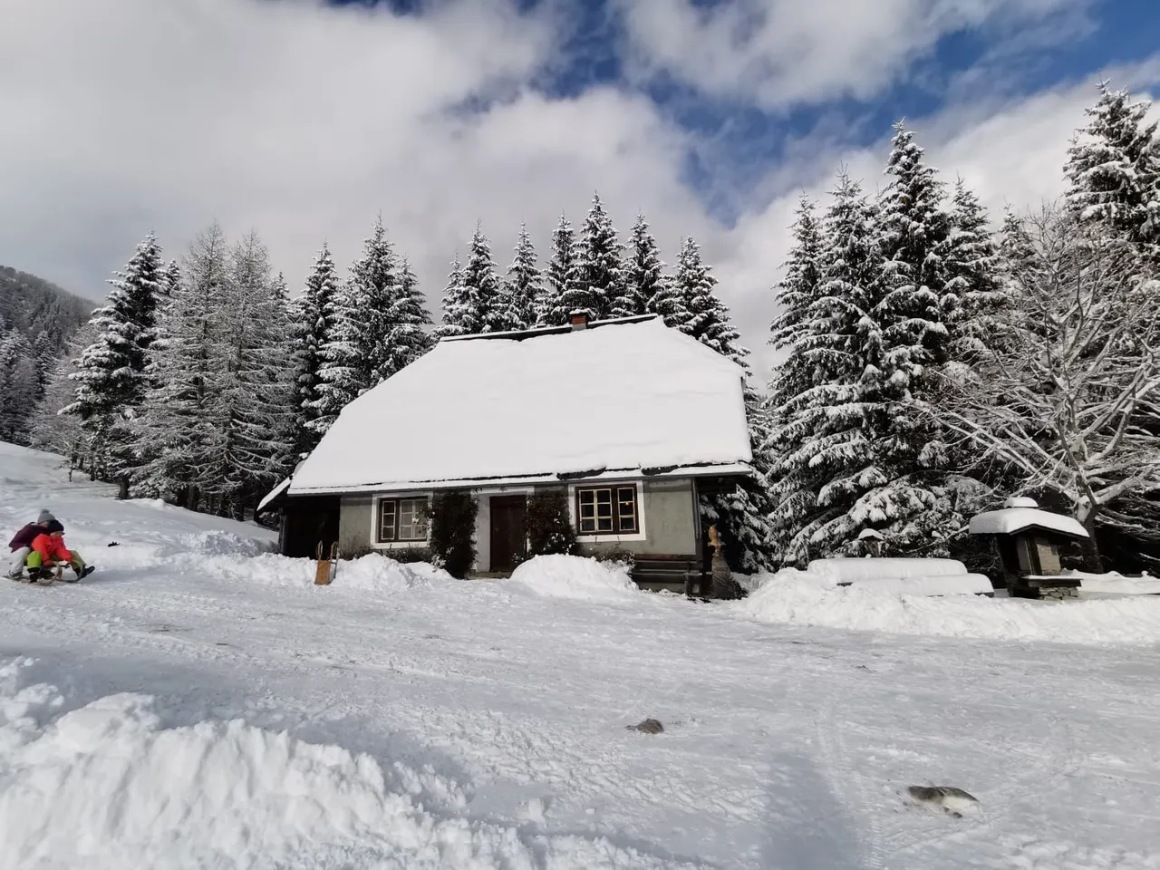 Verschneite Hütte, jemand rodelt