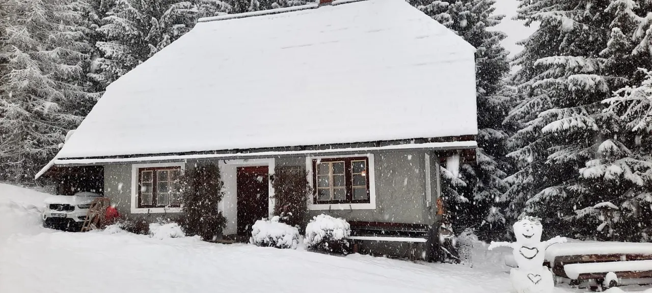Schneemann vor der Hütte im Schneefall
